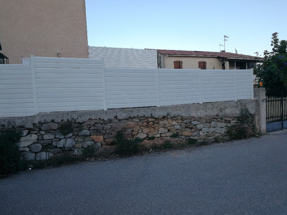 Clôture aluminium blanche occultante devant une maison claire